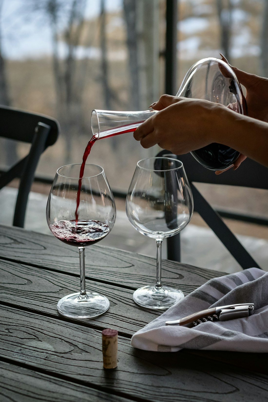 Red wine poured from a decanter into glasses on a long table